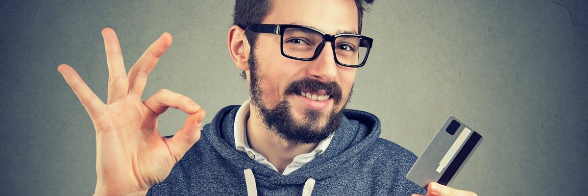 Guy making OK sign holding credit card.