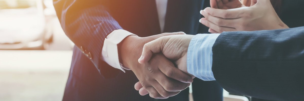 Two people shaking hands and another person clapping.