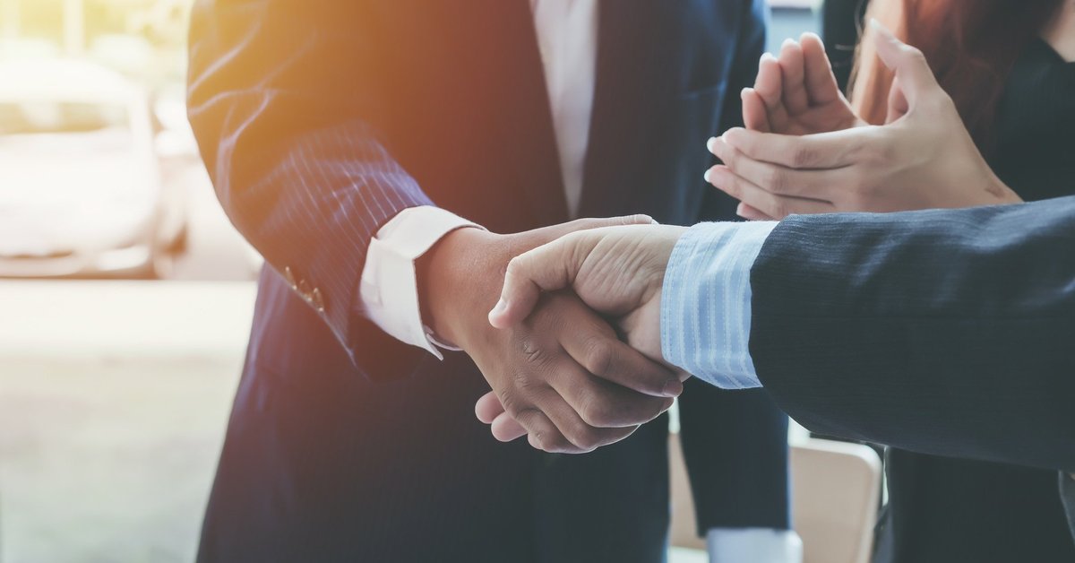 Two people shaking hands and another person clapping.