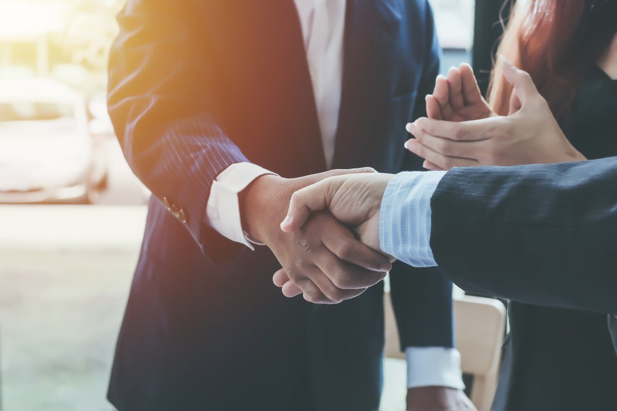 Two people shaking hands and another person clapping.