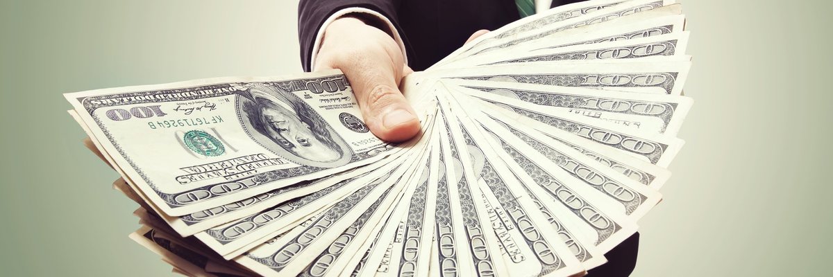 A person holding fanned out hundred dollar bills.