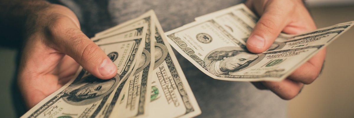 A man holding several hundred dollar bills in his hands,