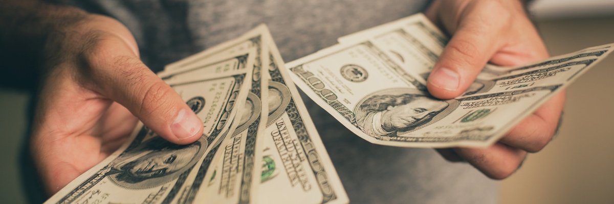 A man holding several hundred dollar bills in his hands,
