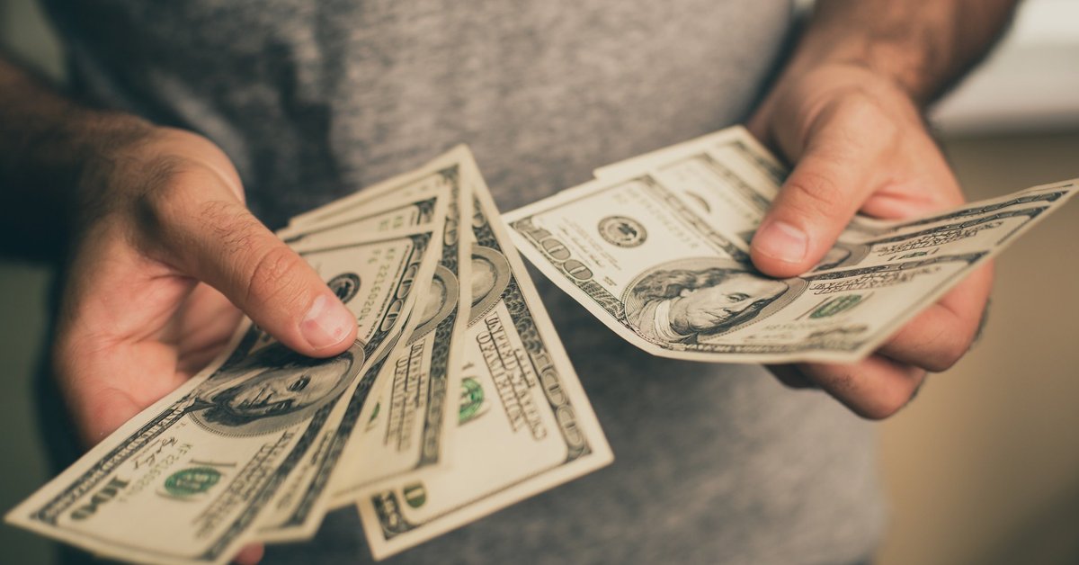 A man holding several hundred dollar bills in his hands,