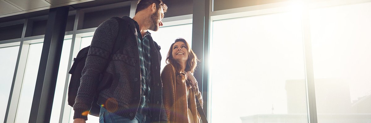 A happy couple holding hands while walking in an airport.