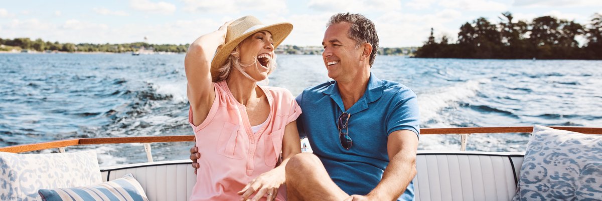 Mature happy couple on the back of a boat in the water.