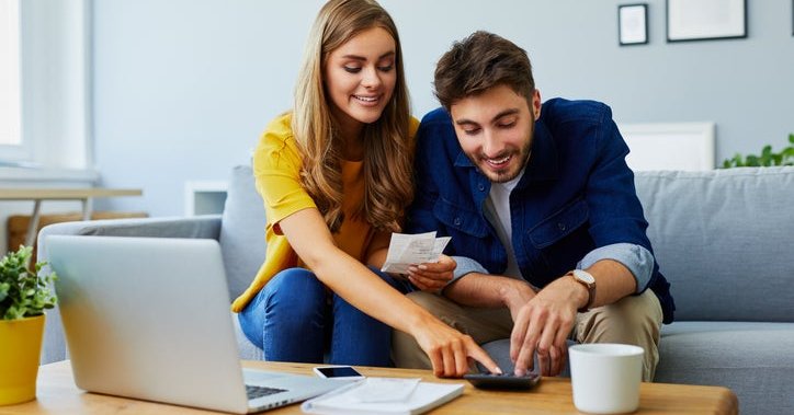 A happy couple with a calculator and bills.