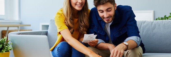 A happy couple with a calculator and bills.