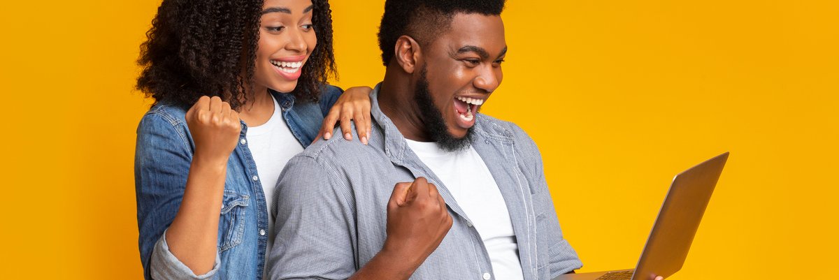 Happy couple celebrate while looking at laptop screen.