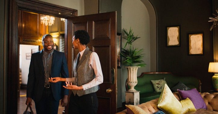 A hotel employee walking a guest into his upgraded hotel room.