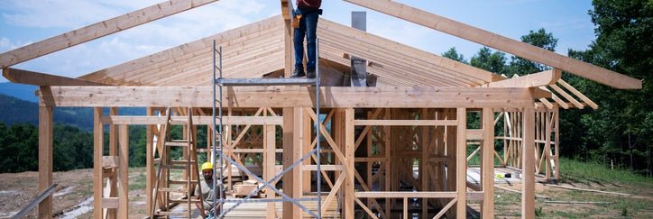The frame of a house under construction with workers on site.