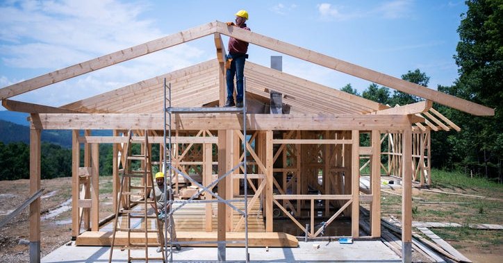The frame of a house under construction with workers on site.