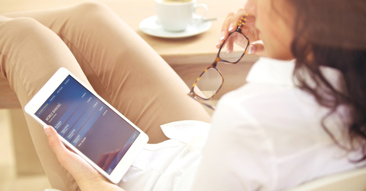 woman sitting looking at mobile bank accounts on tablet