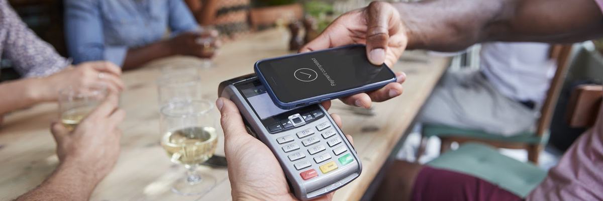 family at restaurant paying with mobile payment app on phone
