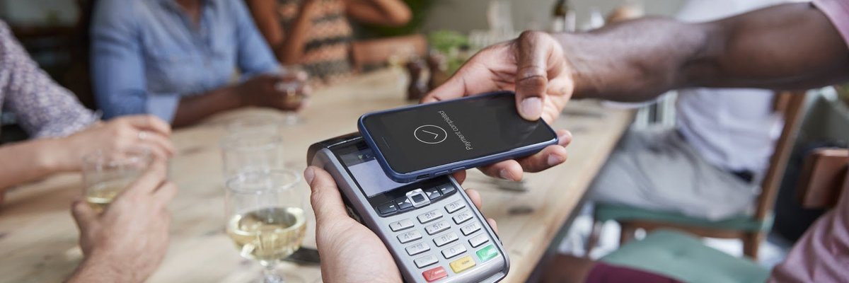 family at restaurant paying with mobile payment app on phone