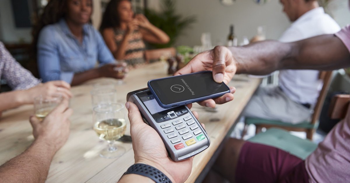family at restaurant paying with mobile payment app on phone