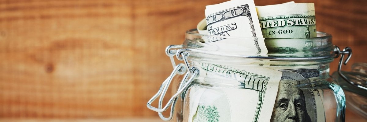 Glass jar full of hundred dollar bills.