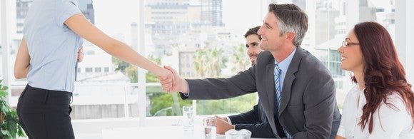 Woman shaking hands with employer during job interview.