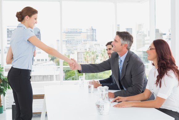 Woman shaking hands with employer during job interview.