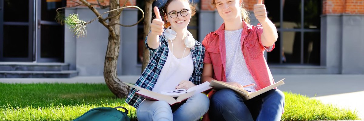 male and female student smiling and giving a thumbs up