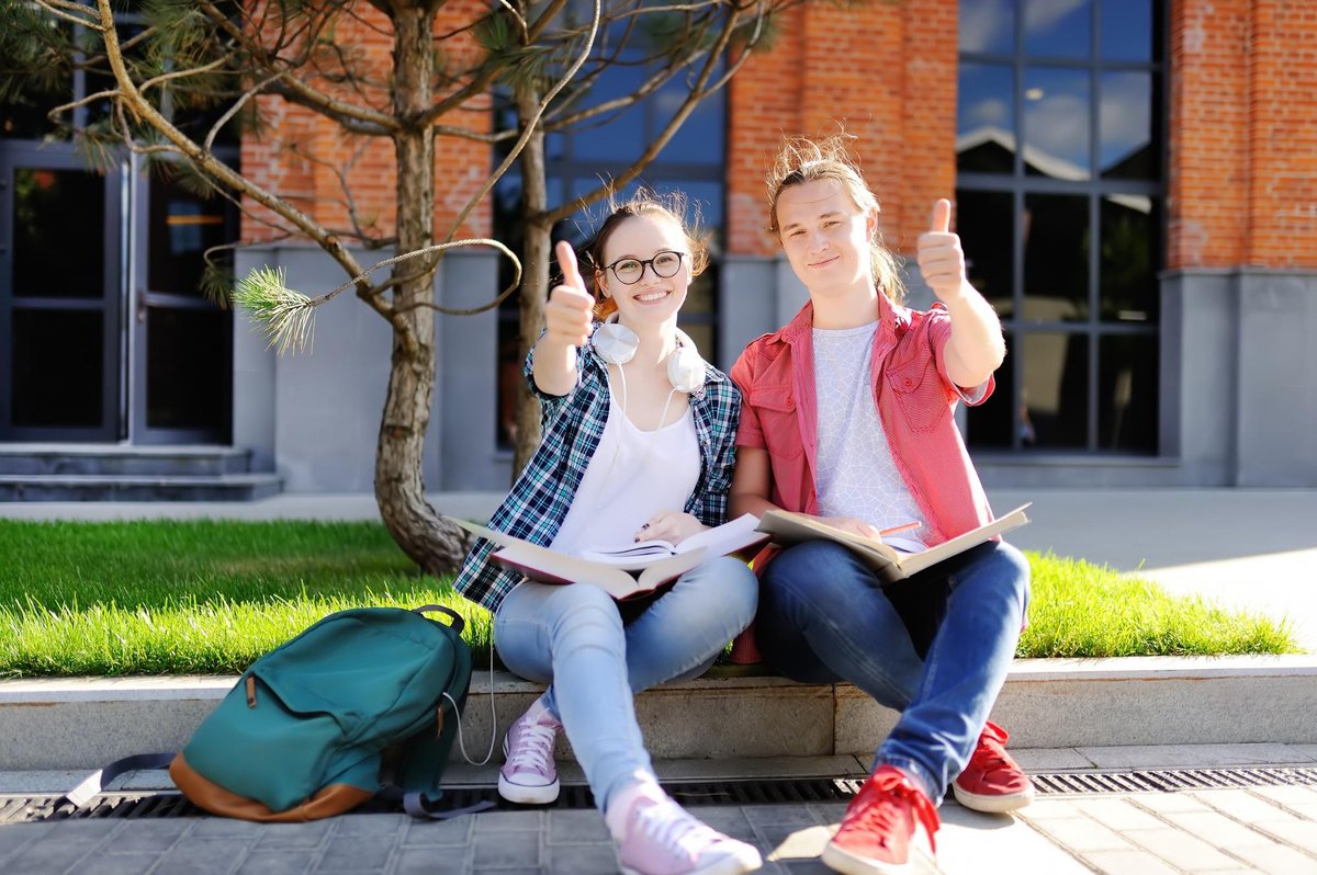 male and female student smiling and giving a thumbs up