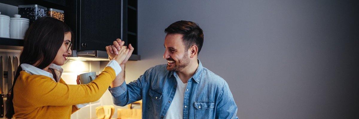 man and woman high five in a kitchen -- couple celebrating success goal