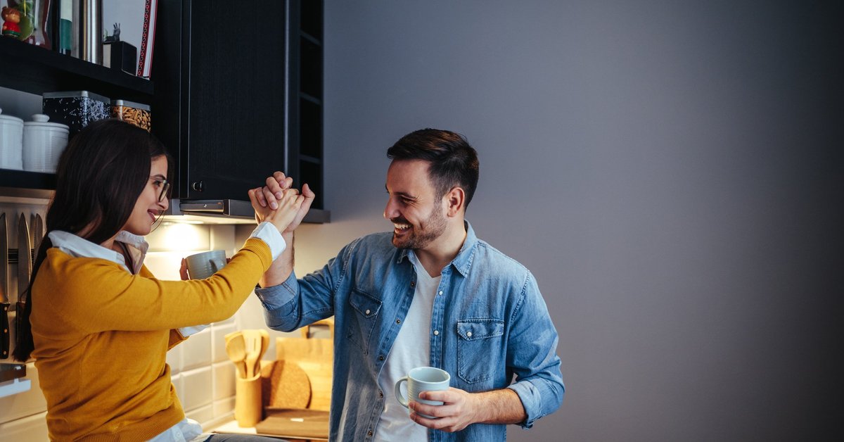 man and woman high five in a kitchen -- couple celebrating success goal