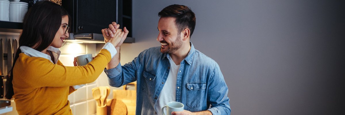 man and woman high five in a kitchen -- couple celebrating success goal
