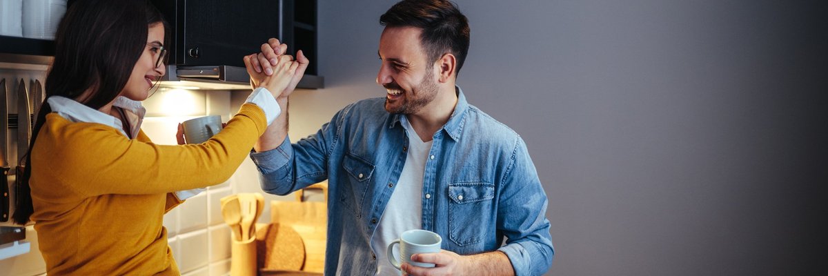 man and woman high five in a kitchen -- couple celebrating success goal