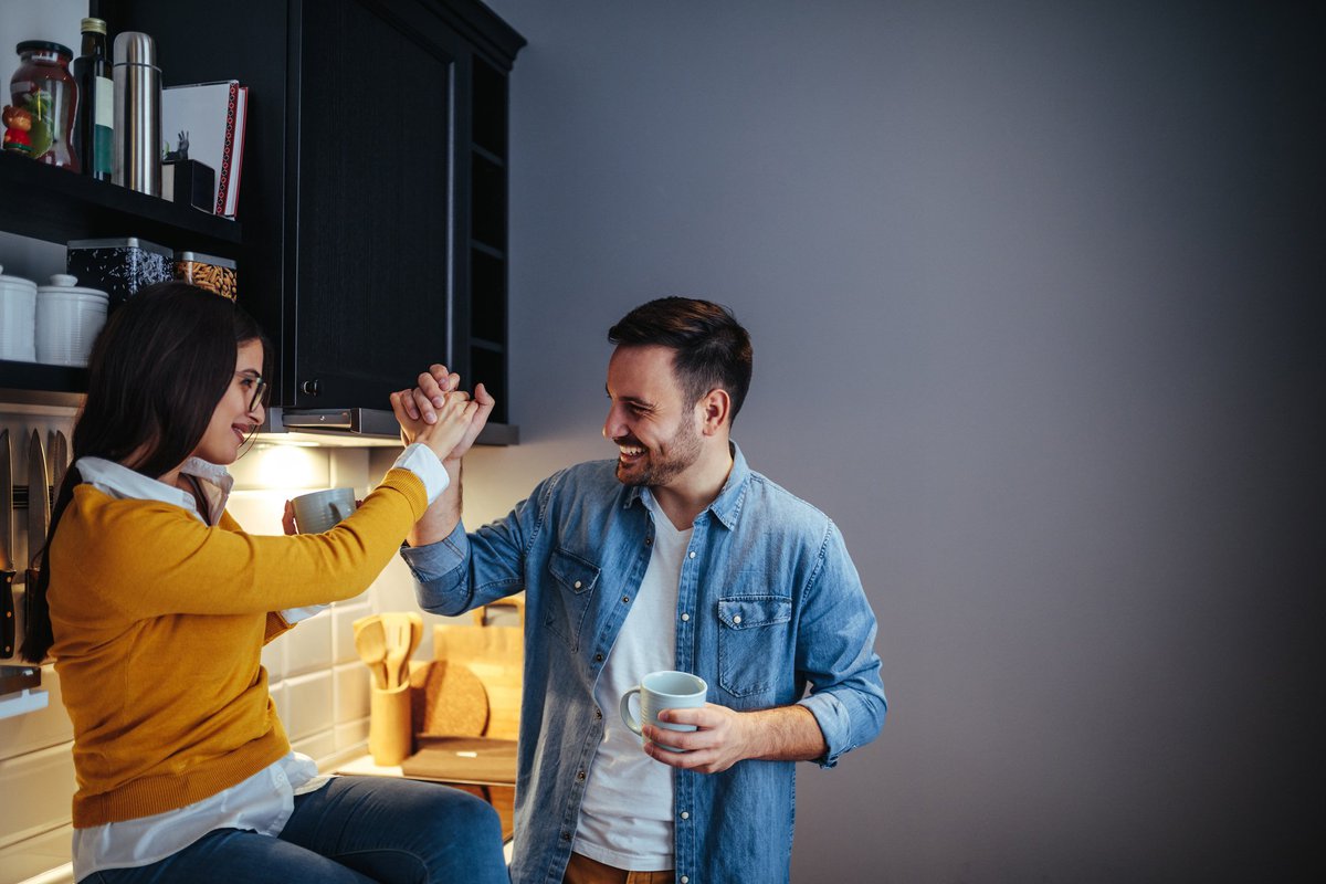 man and woman high five in a kitchen -- couple celebrating success goal