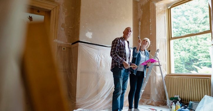 A man and woman looking around a room that's being renovated.