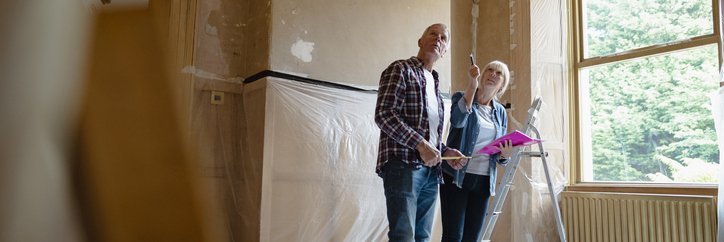 A man and woman looking around a room that's being renovated.
