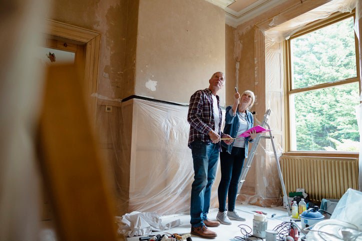 A man and a woman looking around a room being renovated.
