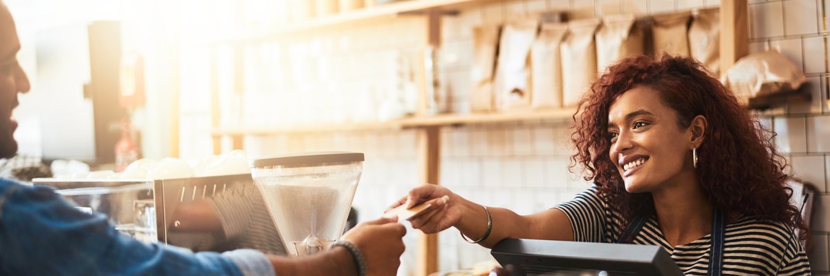 A man handing his credit card to the cashier at a coffeeshop.