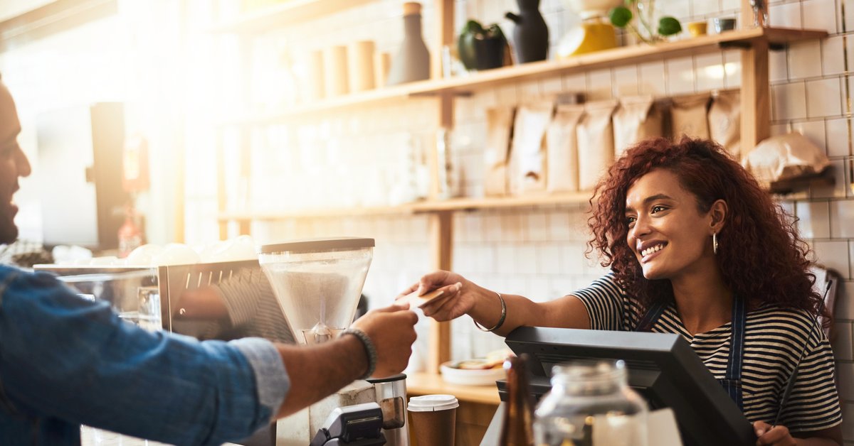 A man handing his credit card to the cashier at a coffeeshop.