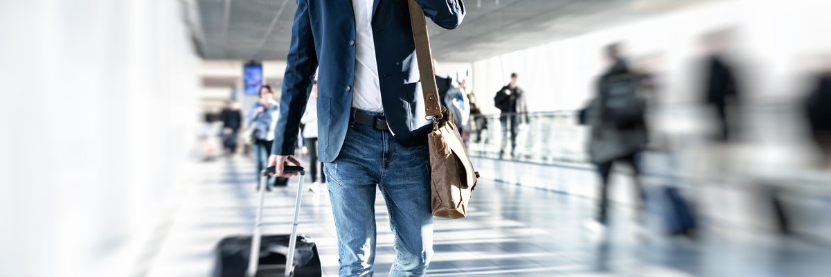 man in airport with suitcase and on the phone 