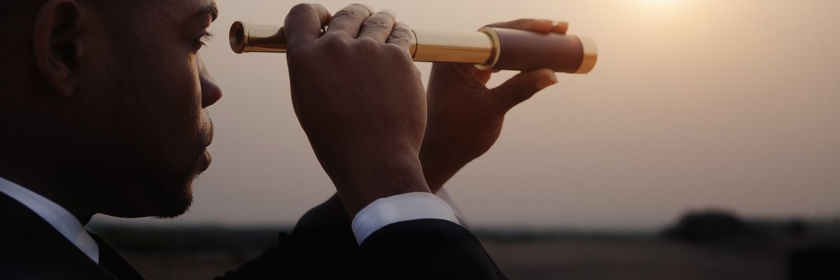 man in business suit looking through telescope toward horizon.