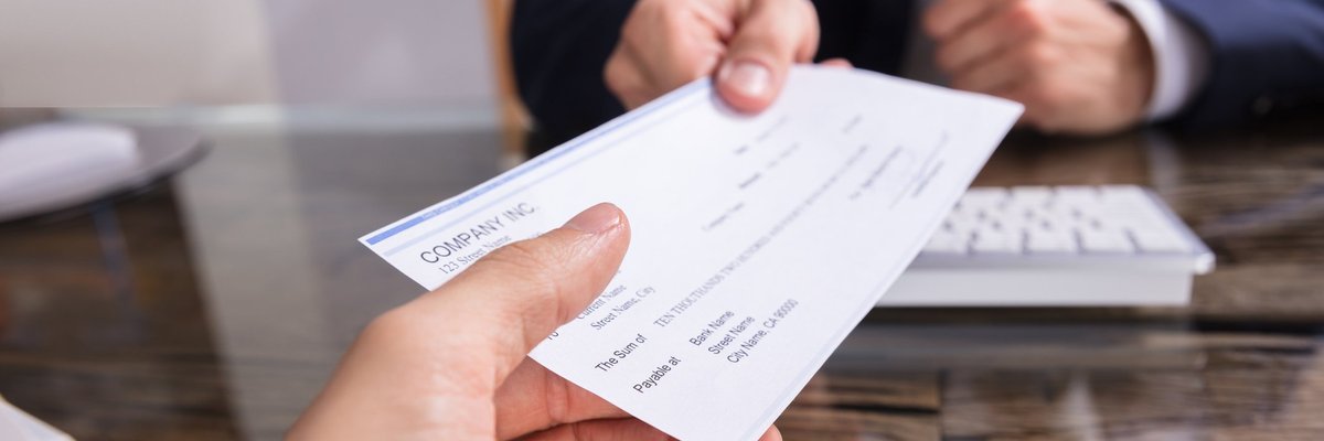 Man in suit handing over a paycheck