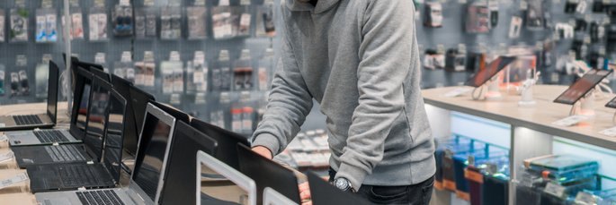 A man testing out laptops in an electronics store.