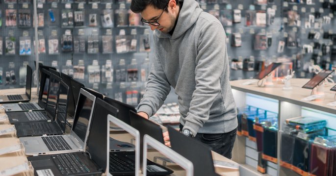 A man testing out laptops in an electronics store.