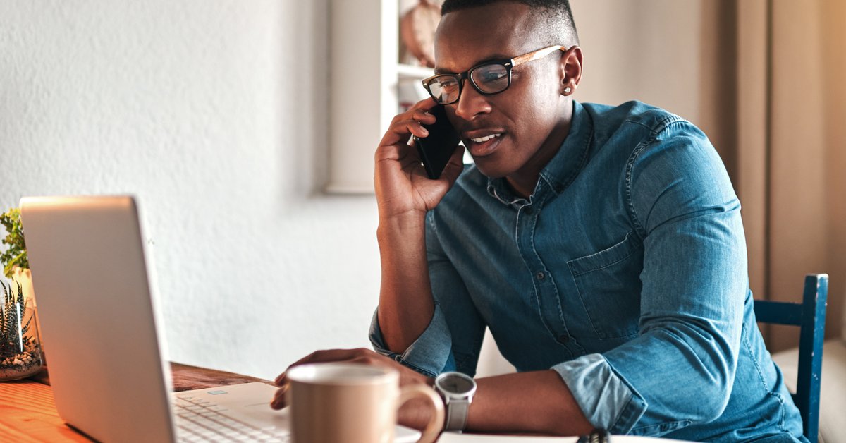A man on a phone call while sitting in front of his laptop.