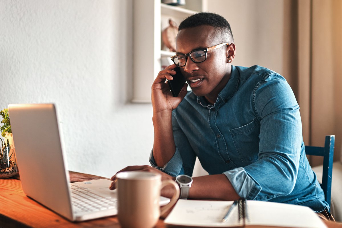 A man on a phone call while sitting in front of his laptop.