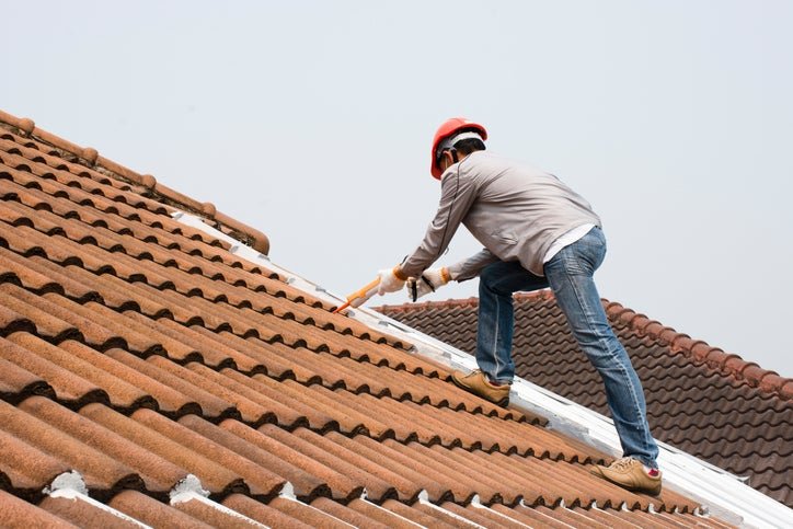 A man in a hard hat working on a tile roof.