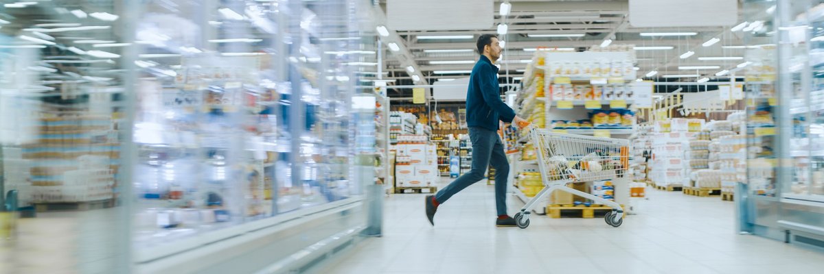 A man pushing a shopping cart through the aisles of a warehouse store.
