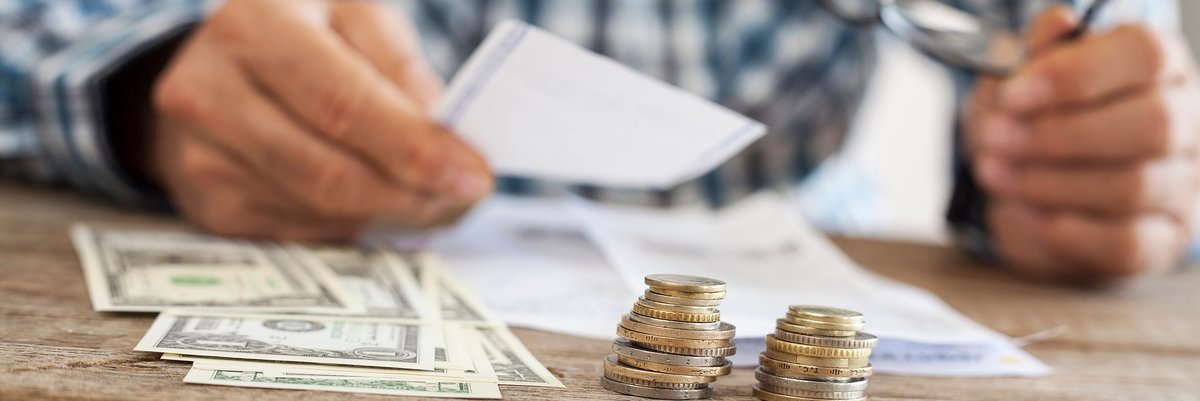 Man sitting at table with dollar bills and coins in front of him.