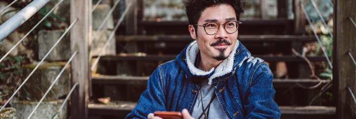A man sitting on stairs in a park and holding a cell phone in his hand.