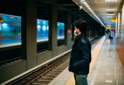 man standing on subway platform wearing a mask due to coronavirus pandemic.
