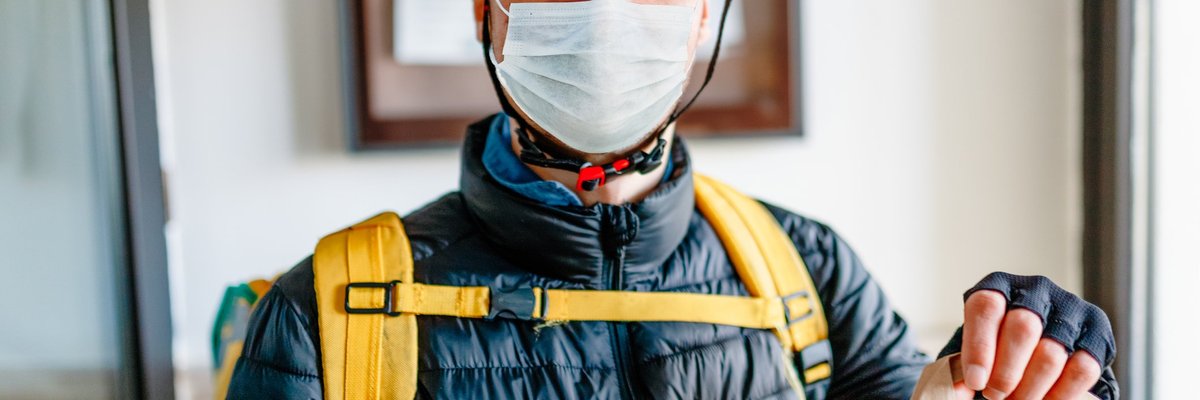 A man wearing a medical mask and delivering a bag of food.
