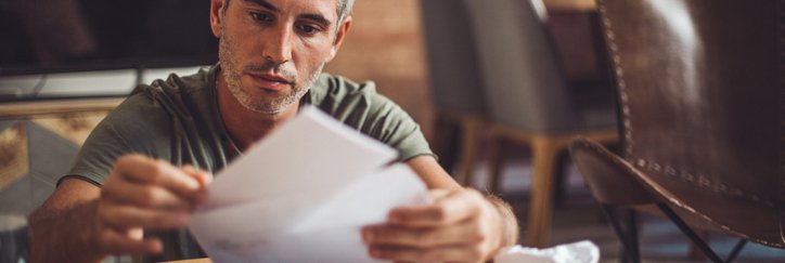 A man sitting at a desk and placing payment for a bill in an envelope.
