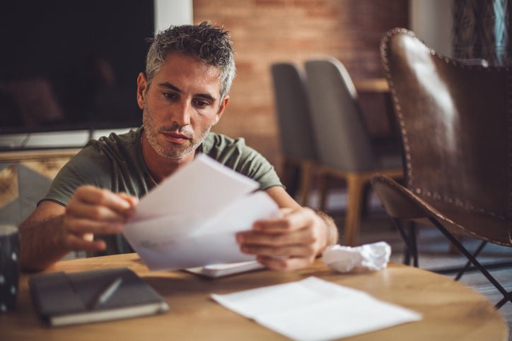 A man sitting at a desk and placing payment for a bill in an envelope.